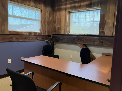 Photograph of Study Room C. Part of the L shaped desk can been seen, as well as two windows and three chairs.