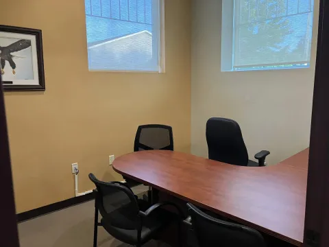 Photograph of Study Room F. Part of the L shaped desk can be seen, two windows, 3 chairs and a picture of an eagle.